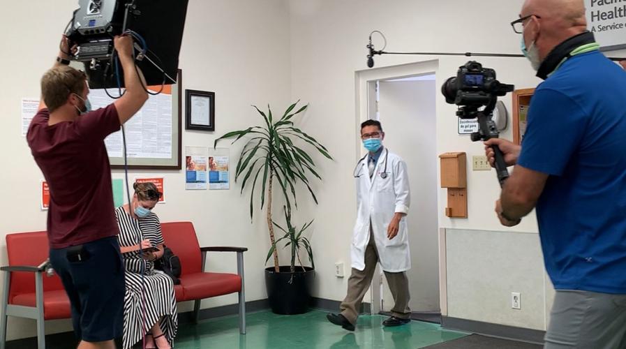 Video crew filming doctor inside building.